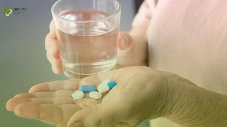 Мужчина со стаканом и таблетками в руках